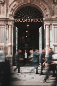 Dynamic urban scene capturing motion at Grand Pera entrance in Istanbul's bustling Beyoğlu district.