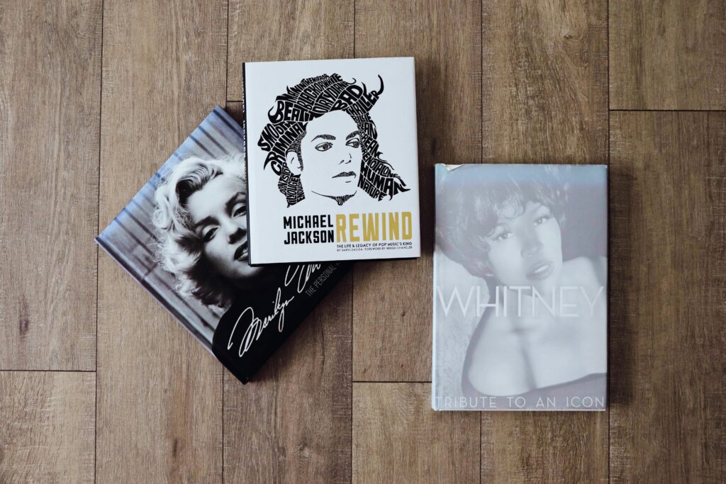 pexels-photo-15269524-15269524 Books featuring Marilyn Monroe, Michael Jackson, and Whitney Houston on a wooden floor.