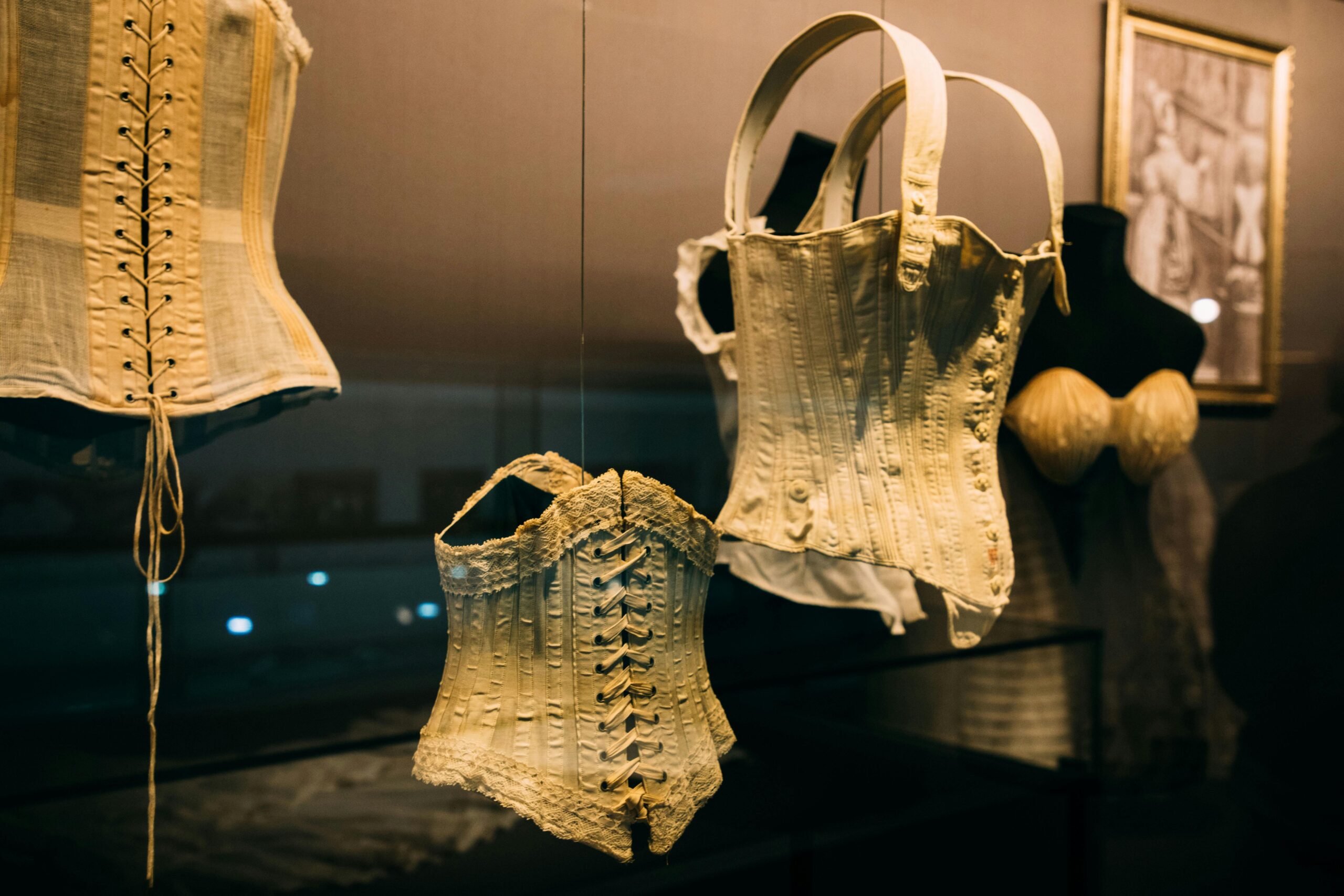 A collection of vintage corsets displayed in a museum exhibit highlighting historical fashion.