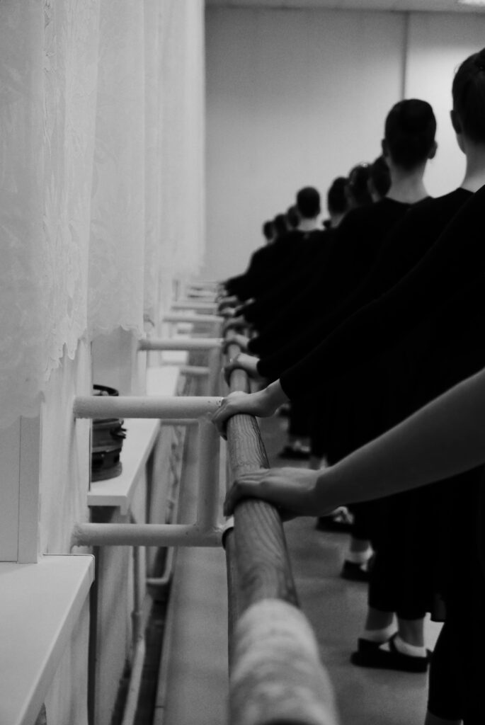 A group of ballet dancers practicing at the barre indoors, showcasing grace and synchronicity.